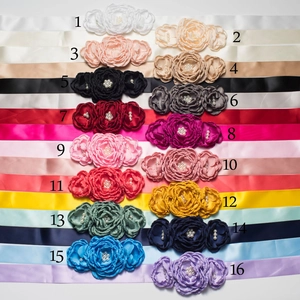 Vue à plat de 16 ceintures en satin coloré avec fleurs et perles pour enfants de luxe