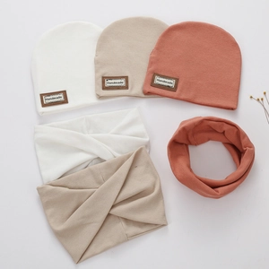 Detail showing ribbed knit baby hat and scarf with handmade brown leather label