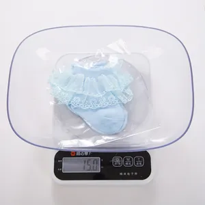 Macro view of light blue baby socks with lace trim weighing 15.0g on a digital scale