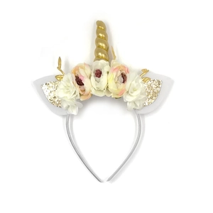 Dettaglio del corno di unicorno dorato e orecchie di peluche con fiori di seta rosa