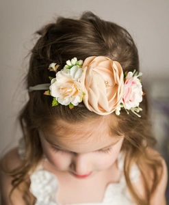 Détail macro d'un bandeau pour bébé avec des fleurs réalistes en tissu et feuilles
