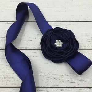 Detailed view of navy blue satin ribbon belt with handmade fabric flower and pearls