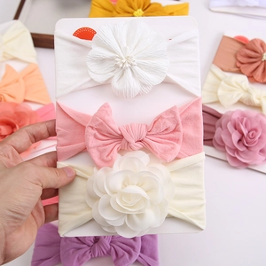 Detail of three baby headbands with pearls, bows and chiffon flowers on card