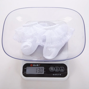 Lightweight white cotton baby socks with delicate lace ruffles, weighing 13 grams