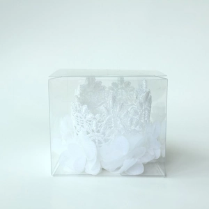 Detail of white lace crown headband with chiffon flower in clear display box