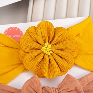 Detailed close-up of yellow baby headband with soft chiffon flower and small pearl beads