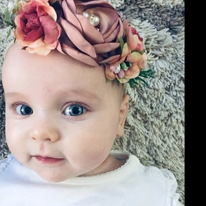 Détail d'un bandeau bébé avec fleurs en soie rose et perles sur ruban en nylon souple