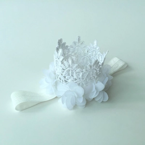 Close-up of white lace crown headband for babies with delicate chiffon flower details