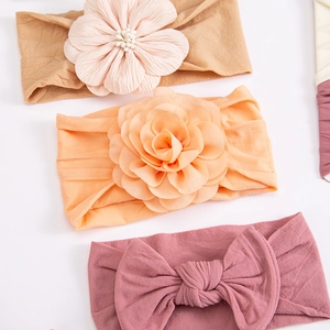 Detailed view of three soft nylon baby headbands with chiffon flowers and bow accents
