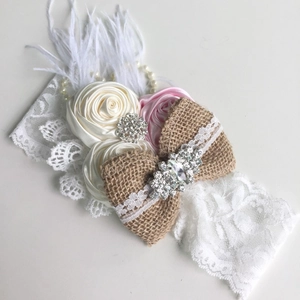 Détail du bandeau en dentelle avec nœud en lin, roses en satin, perles et plumes