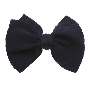 Dettaglio del fiocco in tessuto blu navy con trama a nido d'ape per fascia da neonata