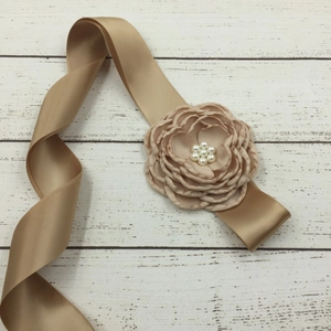 Detail of champagne gold satin sash featuring a handmade fabric flower with pearl beads
