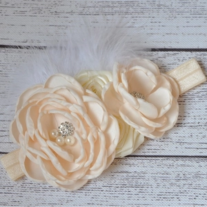 Détail d'un bandeau pour bébé avec fleurs en satin, perles, strass et plumes douces
