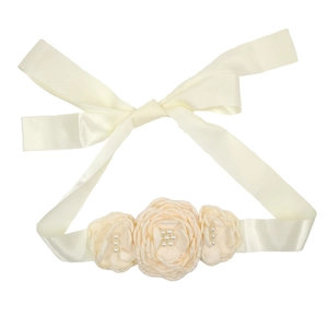Détail de roses en tissu crème avec petites perles sur un ruban de soie élégant