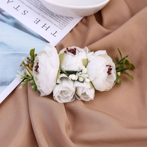 Detailansicht weißer Stoffblumen und grüner Blätter auf warmem braunem Strukturhintergrund