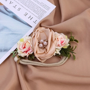 Détail d'un bandeau bébé en nylon avec roses en soie rose et décorations de perles
