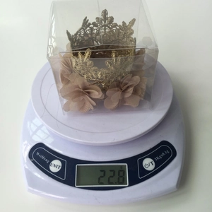 Detail showing a mini gold lace crown with chiffon flowers weighing 22.8g in a box