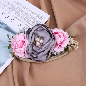 Détail d'un bandeau en nylon pour bébé avec fleurs en soie et accents de perles