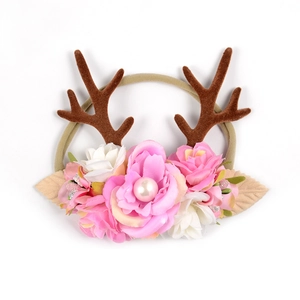 Détail d'un bandeau bébé avec bois de renne marron, fleurs roses et accents de perles