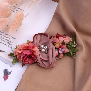 Détail d'un bandeau bébé fleurs roses en tissu avec perles blanches et strass