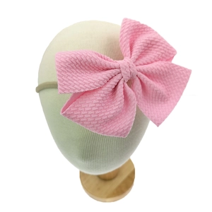 Detail eines rosa Baby-Stirnbandes mit großer Schleife aus Waffelstrick-Stoff