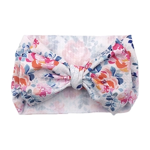 Close-up of baby floral headband featuring a large bow and soft textured knit fabric