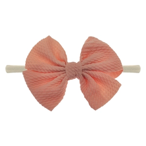 Detail der korallenrosa Waffel-Schleife auf weichem Nylon-Stirnband für Babys
