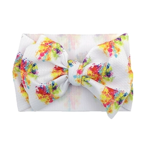 Detailed view of baby headband with a colorful ink splatter print on a white large bow