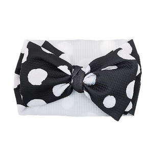 Detailed view of the large black polka dot bow on the white elastic baby headband