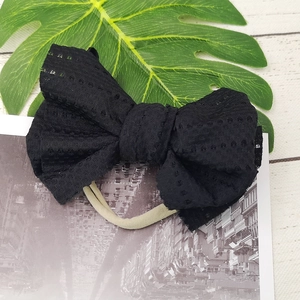 Close-up of black lace bow hairband with soft nylon strap for baby girls and infants