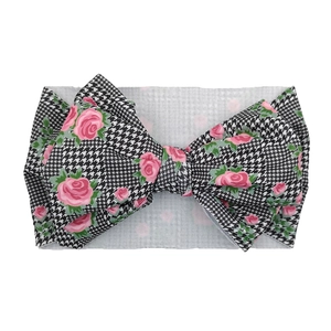 Macro detail of infant bow headband with pink rose pattern and black houndstooth print