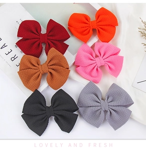 Close-up of six waffle texture hair bows in assorted autumn colors on a minimalist desk