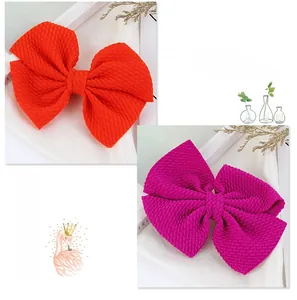 Detailed macro view showing the waffle textured fabric of the orange and rose hair bows