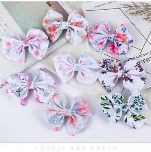 Detailed view of eight assorted waffle fabric bow clips with floral and flamingo patterns