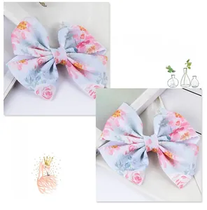 Detail of floral fabric bow hair clip with pink roses on a light blue background