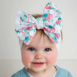 Detail of floral infant headband with large bow and soft textured fabric on a baby