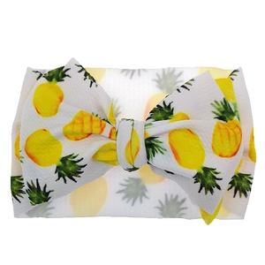 Detailed macro view of white ribbed knit baby headband with yellow pineapple pattern bow