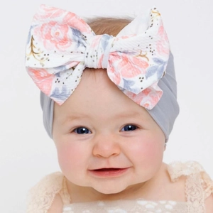 Close-up of baby girl wearing grey turban headband with large floral print bow