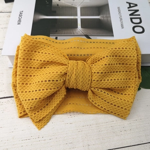 Detail eines hellgelben Spitzen-Stirnbands mit großer handgefertigter Schleife für Babys