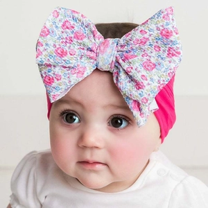Close-up of a soft elastic baby headband with a vibrant magenta bow and floral pattern