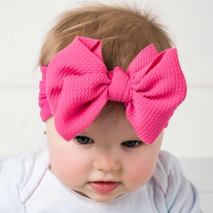 Detail of peach red waffle texture baby bow headband worn by an infant model