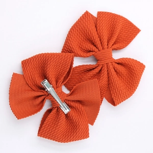 Detail of bright orange handmade hair clips with waffle texture and metal alligator clips