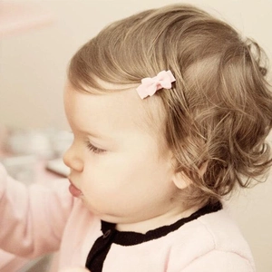 Gros plan d'une pince à cheveux rose clair avec nœud papillon sur les cheveux d'un bébé