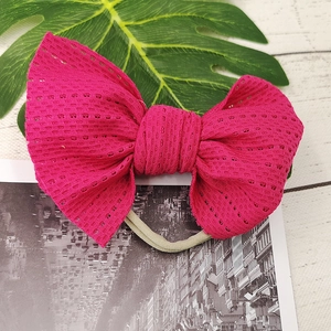Detailed macro view of large rose red lace mesh bow on a beige nylon baby headband
