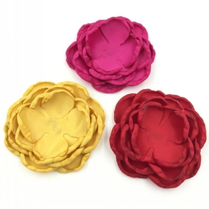 Détail de trois fleurs en tissu faites main en rouge et jaune avec centres de perles
