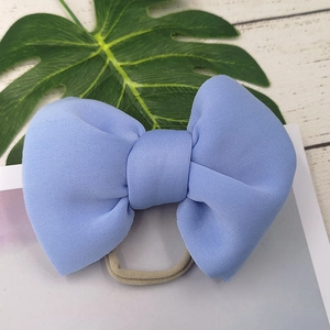 Light blue fabric bow headband for infants with elastic band on a wooden table