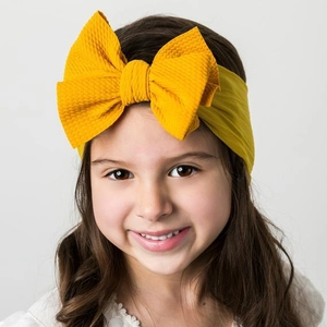 Detail of baby headband with ginger yellow waffle texture bow on a soft elastic nylon band