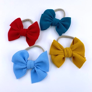 Close-up of four nylon headbands for baby girls featuring textured waffle bow details