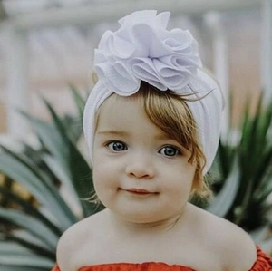 Gros plan d'un bandeau blanc pour bébé orné d'un grand nœud floral en tissu élastique