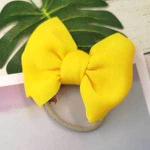 Detail of a vibrant yellow puffer bow headband with seamless elastic band for infants